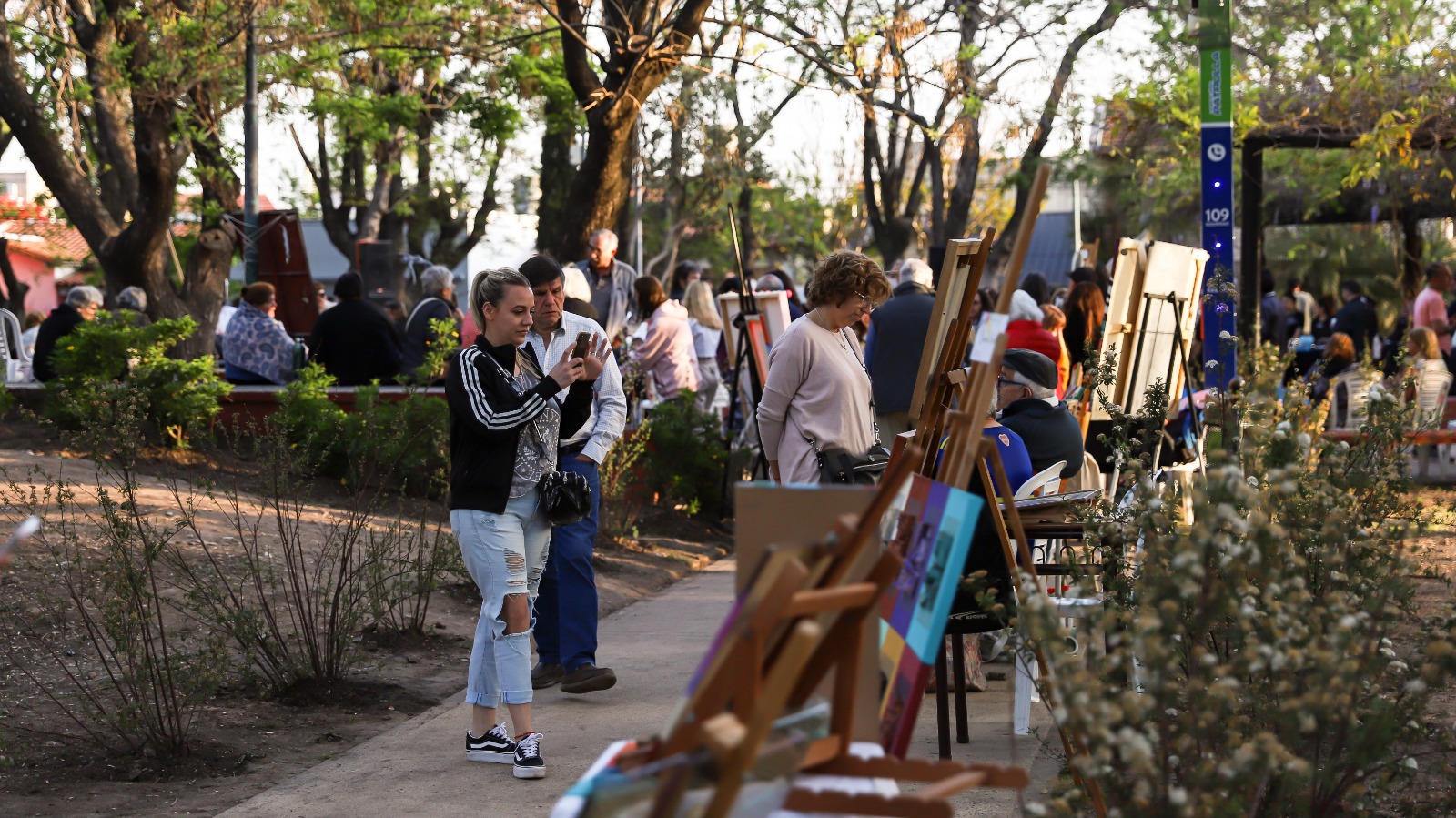 Visitantes disfrutando de la exposición de arte “CarapArt” en Carapachay, observando diversas obras y participando en actividades culturales en un ambiente al aire libre.