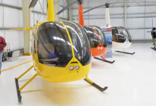 Vista de helicópteros alineados en un hangar moderno en Don Torcuato, destacando su utilidad en misiones de seguridad y salud.