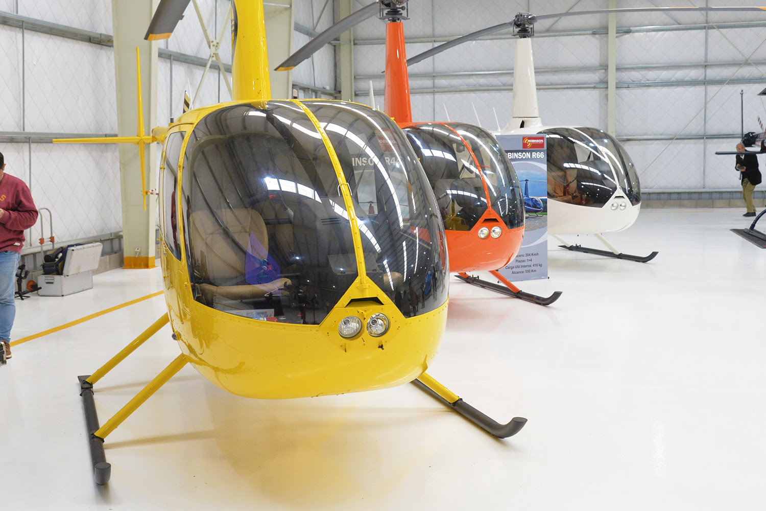 Vista de helicópteros alineados en un hangar moderno en Don Torcuato, destacando su utilidad en misiones de seguridad y salud.