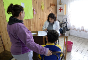 Una mujer y un niño siendo atendidos por una trabajadora de salud en el operativo de servicios del Municipio de Tigre en Don Torcuato.