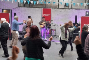 Un grupo de personas disfrutando de una tarde de música y baile en la Sociedad de Fomento de Villa La Ñata durante el ciclo Domingos de Peña, con una banda tocando en el fondo.