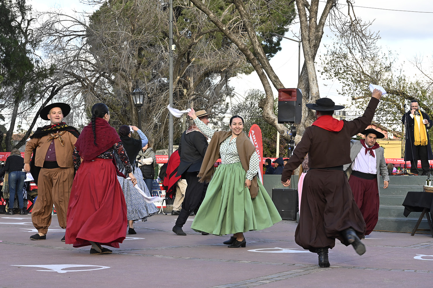 Grupo de personas vestidas con trajes folclóricos tradicionales bailando en una plaza durante el ciclo 'Domingos de Peña' organizado por el Municipio de Tigre.