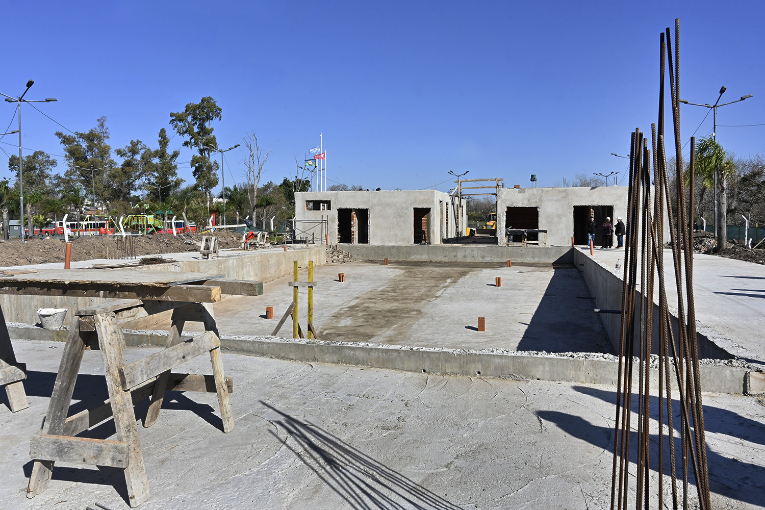 Obreros trabajando en la construcción de un nuevo natatorio en General Pacheco, con estructuras de concreto y paredes en construcción visible, supervisado por el intendente Julio Zamora.