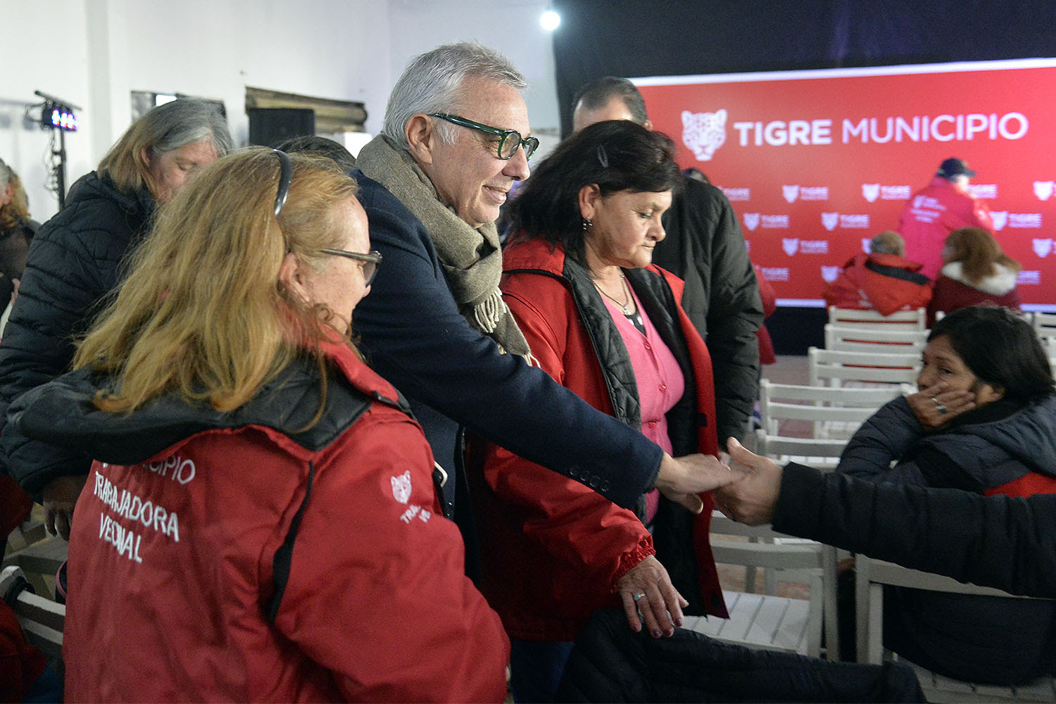 El intendente de Tigre, Julio Zamora, estrechando la mano de una trabajadora vecinal durante un evento de reconocimiento en el Club Peñarol.