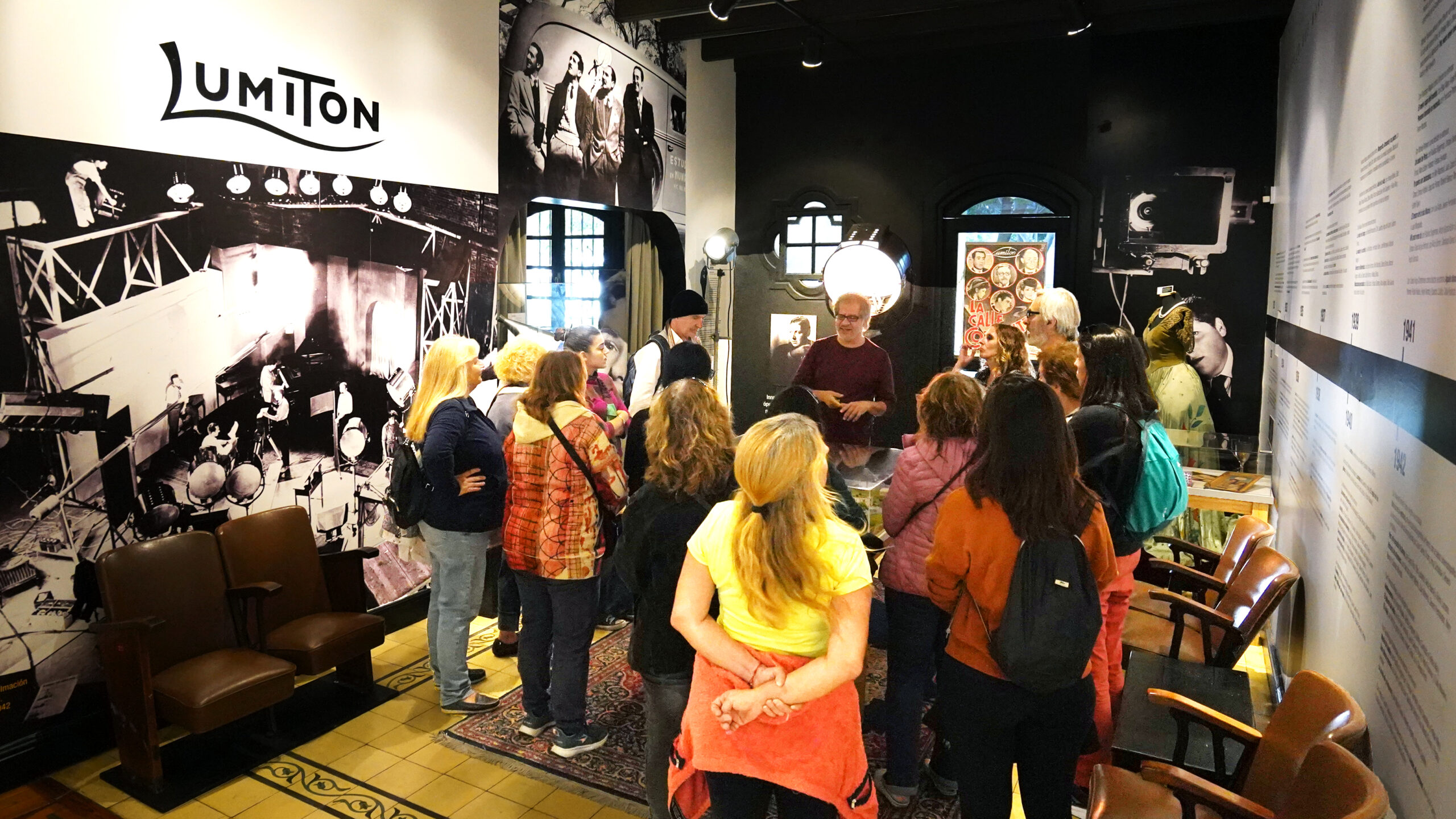 Grupo de personas en una visita guiada en el museo Lumiton, observando artefactos y aprendiendo sobre la historia del cine argentino.